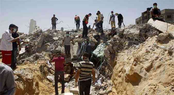 Palestinos trabalham buscando vtimas de ataque areo israelense em escombros de prdio destrudo em Gaza(foto: AFP PHOTO/ SAID KHATIB )