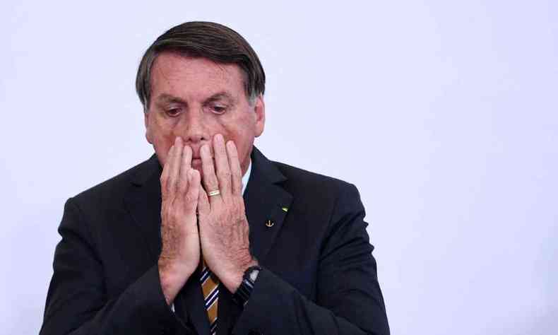 Jair Bolsonaro com as mos n rosto com expresso preocupada