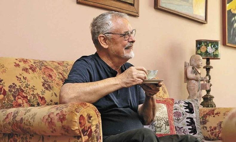 Chef Humberto Passeado toma cafezinho e sorri, sentado em sof� numa sala