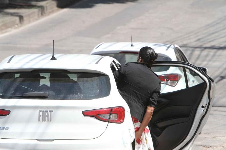 Mulher de blusa preta entra em carro branco