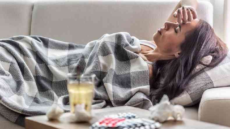 Mulher deitada com sintomas gripais