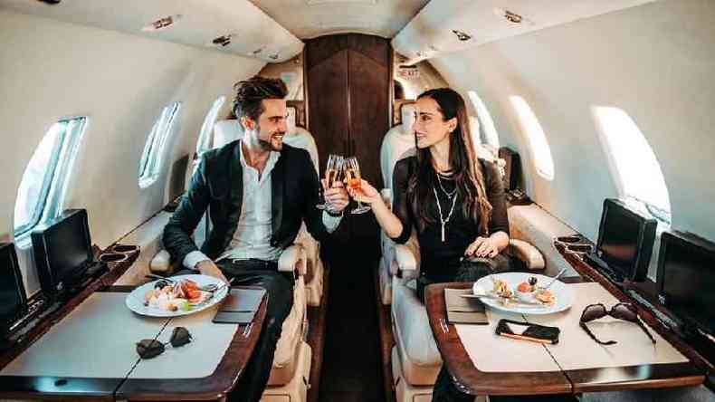 Casal brindando com champanhe em avião particular