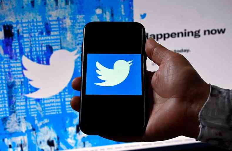 Mo segurando celular com a marca do Twitter