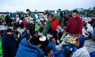 Voluntrios distribuem comida a quem aguardava o transporte para atravessar a fronteira para a ustria(foto: Vladimir Simicek/AFP)