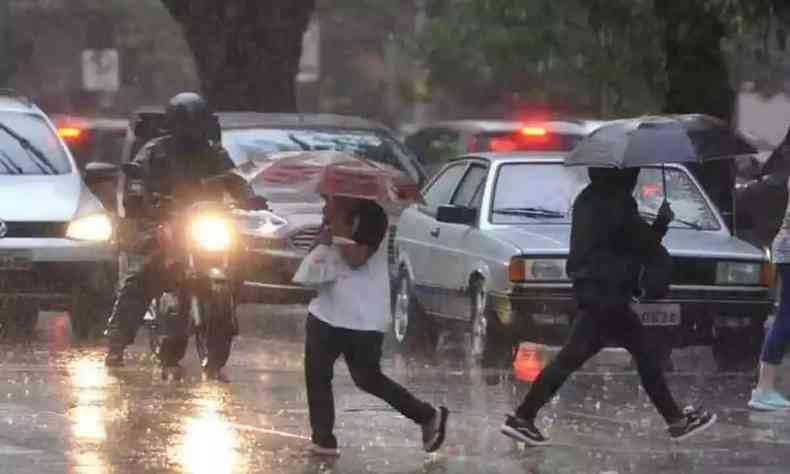 Na foto, pessoas atravessam a rua segurando sobrinhas, na regio Centro-Sul de BH, durante chuva