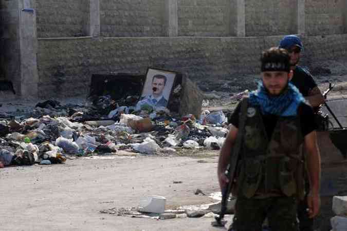 Combatentes rebeldes mostram foto de Assad em uma lixeira na cidade de Aleppo(foto: BULENT KILIC / AFP)