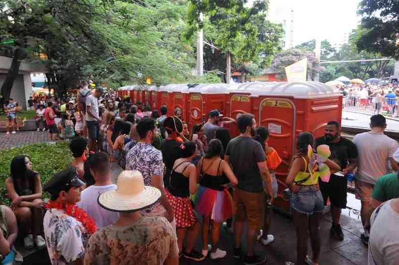 Fila de banheiros qumicos de cor laranja enquanto multido espera para poder utilizar na praa da Savassi, no carnaval de 2019