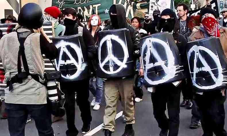Manifestantes em Oakland, nos Estados Unidos, carregam cartazes com smbolos do anarquismo e do movimento hippie(foto: GIROS FILMES/DIVULGAO)