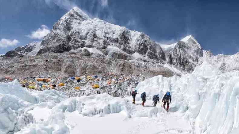 Grupo de alpinistas deixa o acampanhamento base, ao fundo, no monte Everest