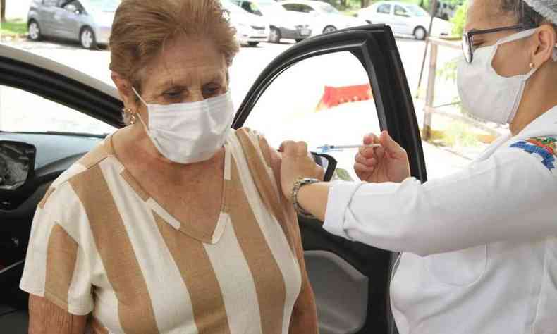 Na foto, enfermeira aplicando vacina no brao da idosa