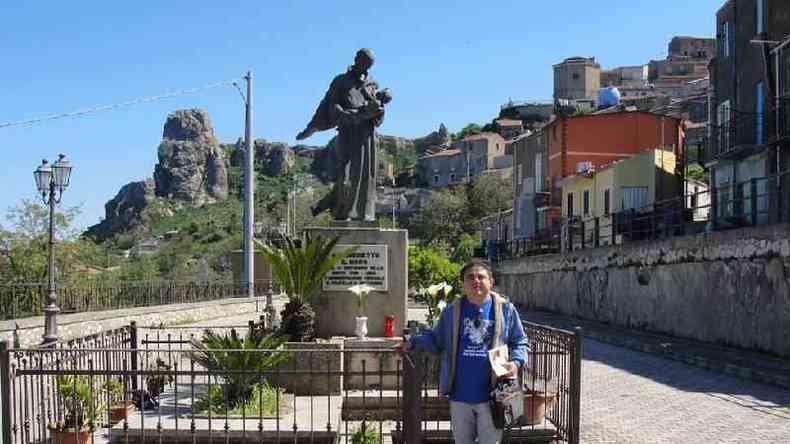 Pesquisador Lira, na Siclia, em frente a esttua em honra a So Benedito em praa sob dia ensolarado