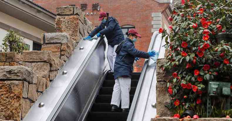 Funcionrias do parque da Disney em Xangai desinfetam escada rolante, na chamada %u201Cfase de reabertura%u201D das atividades no pas asitico (foto: AFP )