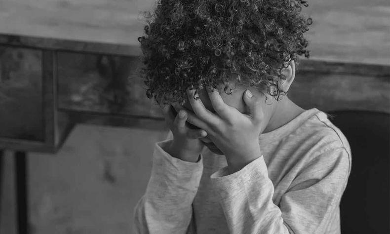 Criana negra escondendo o rosto nas mos