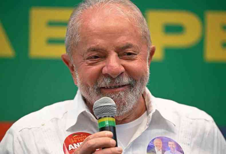 Lula sorri, falando ao microfone em entrevista coletiva