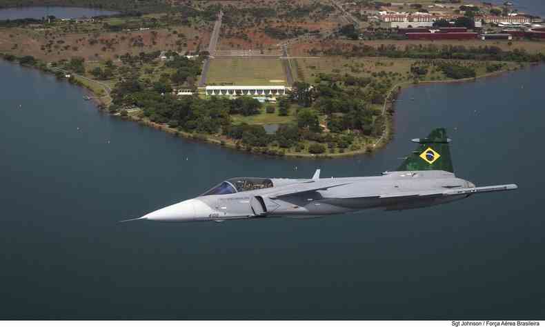 Jato F39E da Fora Area, cinza com asa superior pintada com a bandeira do Brasil, sobrevoando o lago Parano em Braslia