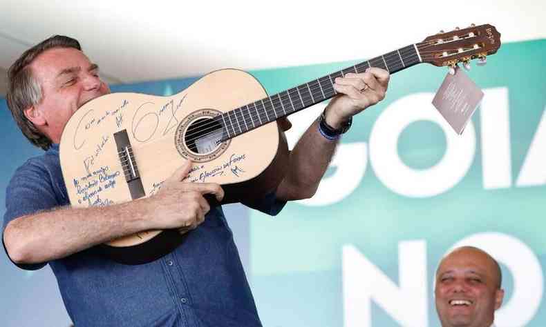 O presidente Jair Bolsonaro brinca com um violo, como se fosse um fuzil