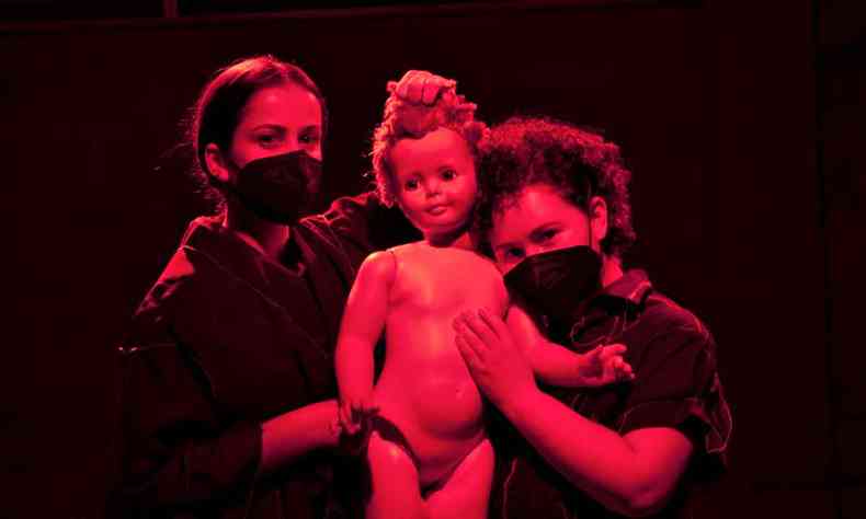 Alunas da Escola de Teatro PUC Minas, Jssica Matos e Ana Verdan seguram boneca, sob luz avermelhada, na pea ''Eclmpsia'' 
