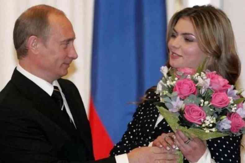 Alina Kabaeva segura buqu de flores ao lado de Vladimir Putin