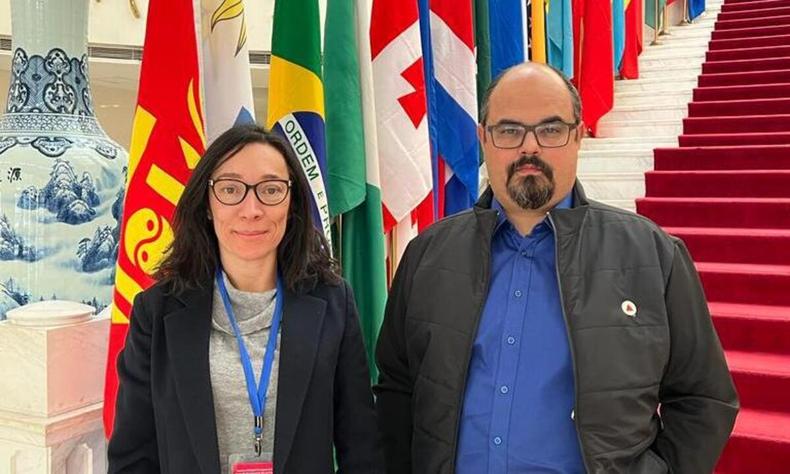 Professor Mateus Simes (Novo) e secretria de Estado de Meio Ambiente e Desenvolvimento Sustentvel, Marlia Melo, em frente a uma escadaria e com uma srie de bandeiras de diferentes pases ao fundo, entre eles Brasil, Uruguai, Costa Rica, Etipia e outros