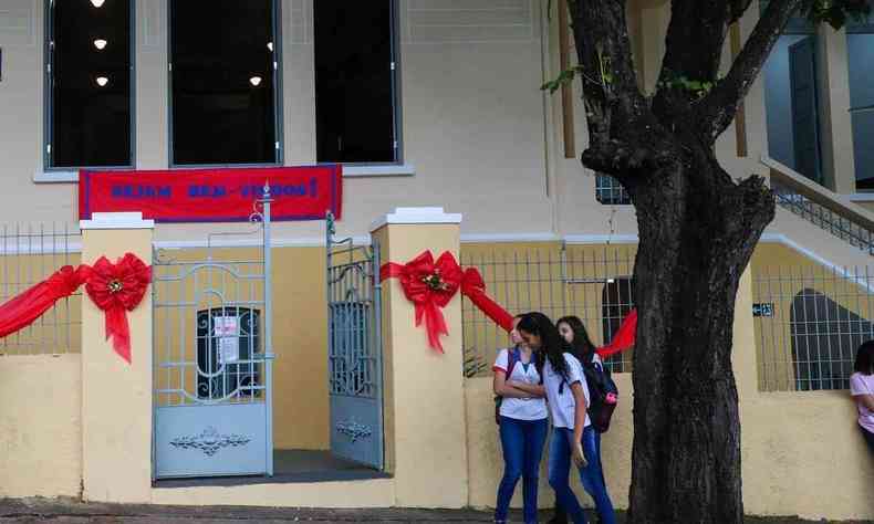 Imagem de alunos em frente a uma escola