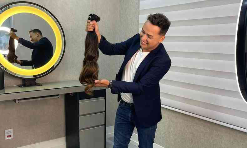 Homem segurando uma peruca de cabelos longos