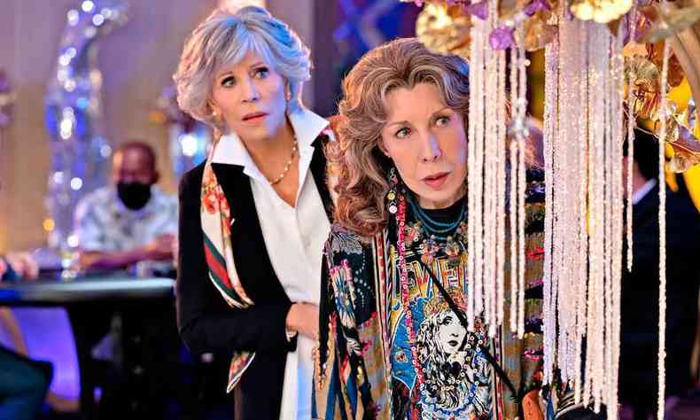 Escondidas atrs de um lustre, as atrizes Jane Fonda e Lily Tomlin fazem expresso de surpresa em cena de 'Grace and Frankie'