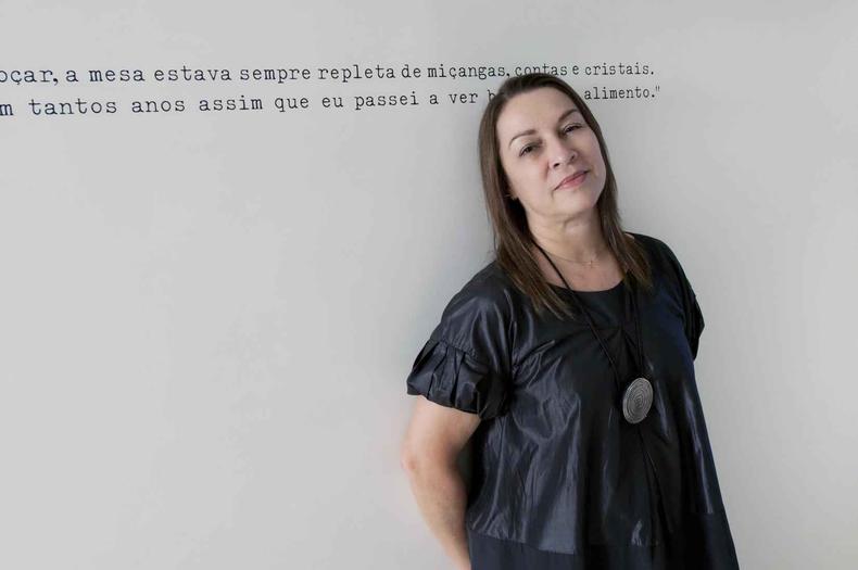 Em seu espaço na Rua Ivaí, na Serra, Mary Arantes recebe o público com a área externa dedicada a atrações gastronômicas(foto: Juliano Arantes/Divulgação) De blusa preta, sentada à mesa, Mary Arantes sorri