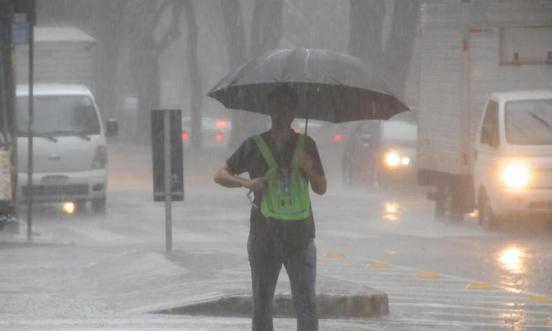 Homem caminha com guarda chuva durante tempestade em Belo Horizonte