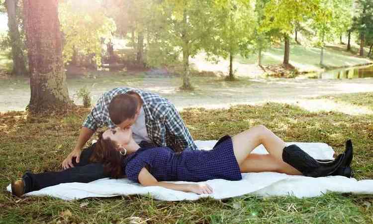 casal ao ar livre, deitado na grama, se beijando