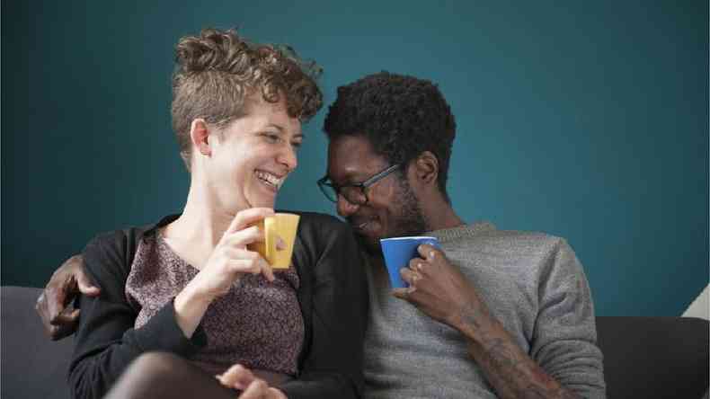 Homem e mulher rindo tomando caf juntos
