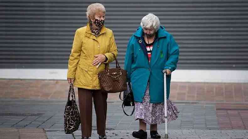 Duas idosas de mscara caminham pela rua