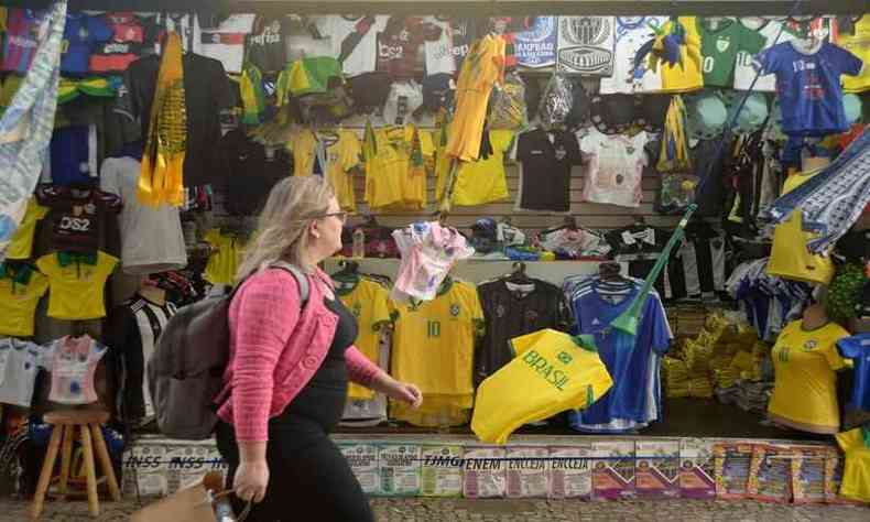 Mulher passando em frente a uma banca de jornal, com camisas da seleo brasileira e artigos de Copa do Mundo  venda