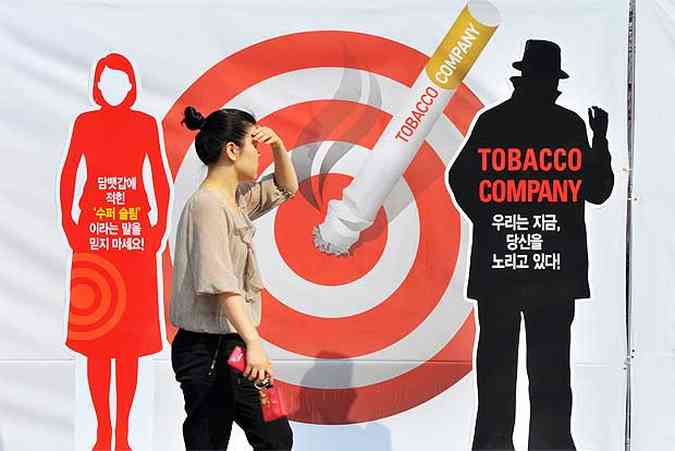 Em Seul, Coreia do Sul, uma mulher  vista ao lado de uma propaganda antitabagista(foto: AFP PHOTO / JUNG YEON-JE)