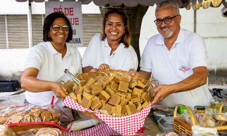 Homem e duas mulheres posam para foto sorrindo e segurando cesta de doces 