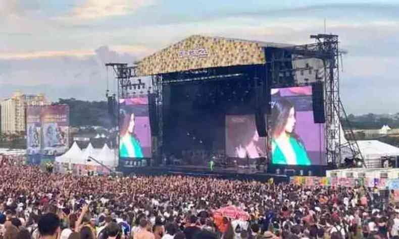 Imagem de um dos palcos do Lollapalooza. H muitas pessoas na plateia e a cantora no palco  MARINA, que veste roupas verdes e aparece no telo.
