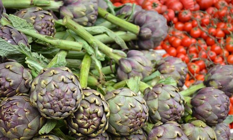 alcachofra e tomate em bancas de uma feira de rua