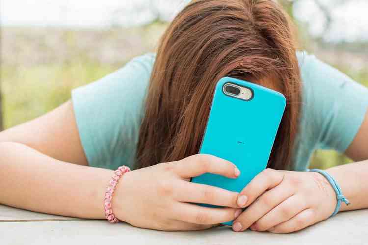 adolescente esconde o rosto atrs do smartphone