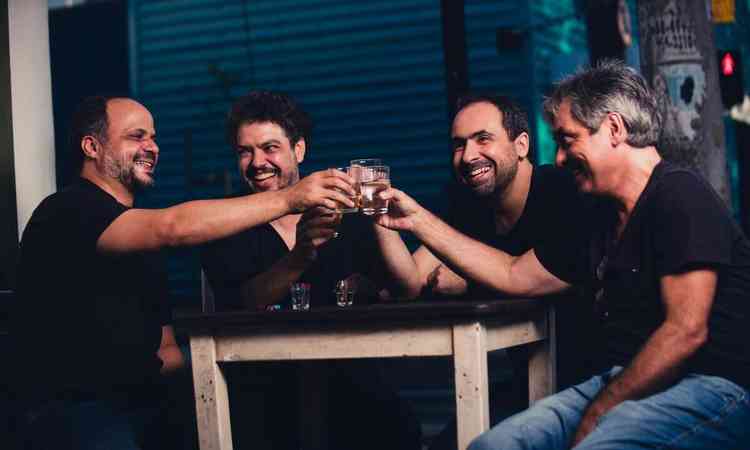 Msicos Alozio Horta, Thiago Delegado, Cristiano Caldas e Andr 'Limo' Queiroz esto sentados  mesa e brindam com copo de bebida
