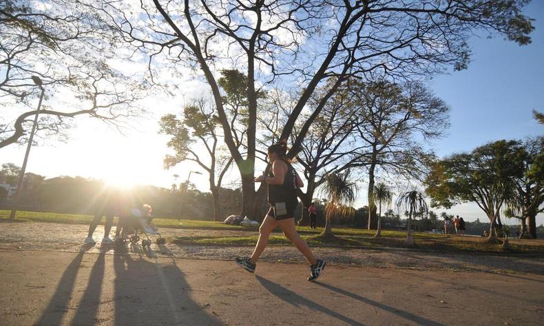 Apesar do inverno hoje foi um dia mais quente do ano em Belo Horizonte(foto: Alexandre Guzanshe/EM/D.A. Press. Brasil. Belo Horizonte - MG.) Pessoa caminhando em primeiro plano, ao fundo, é possível ver o sol atravessando as árvores