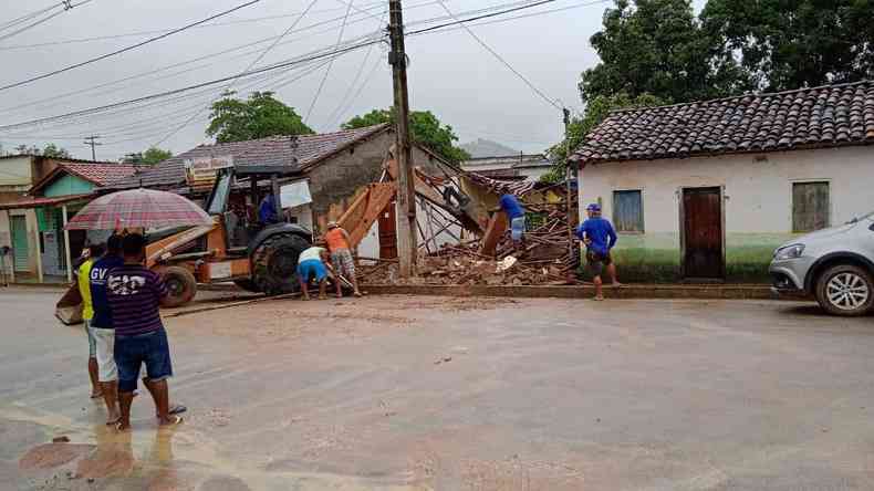 Rua da cidade Machacalis, no Vale do Jequitinhonha, tomada pela enxurrada. Uma casa desmoronou. Uma moradora tenta atravesssar a rua.