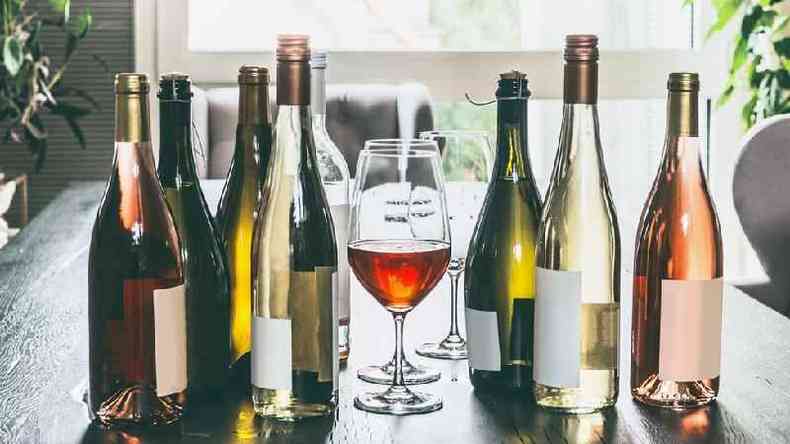 Taa de vinho rodeada por garrafas de vinho