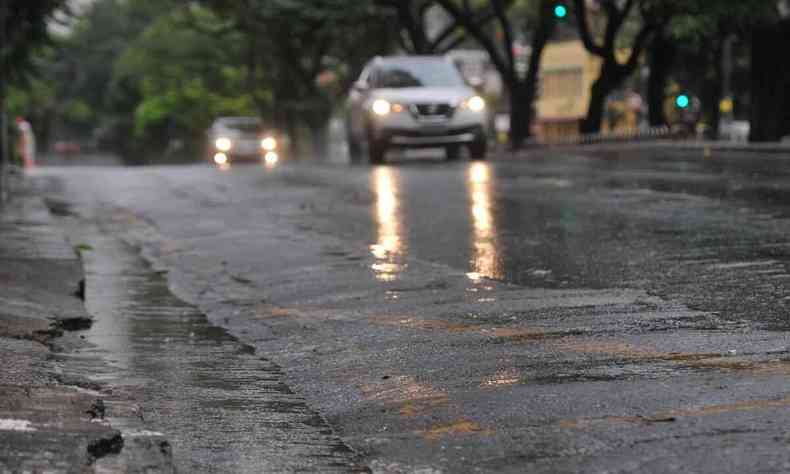 rua em BH com chuva e carro passando 