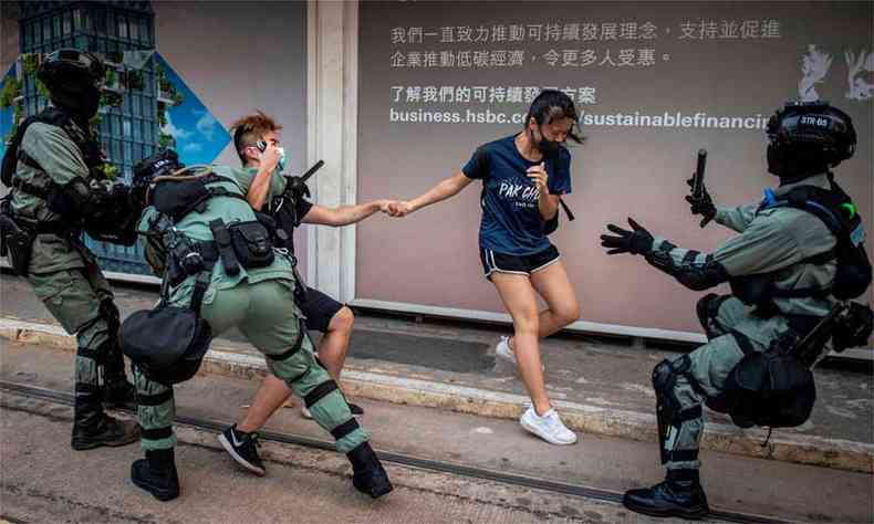 A polcia persegue um casal de mscaras no distrito central de Hong Kong (foto: NICOLAS ASFOURI/AFP)