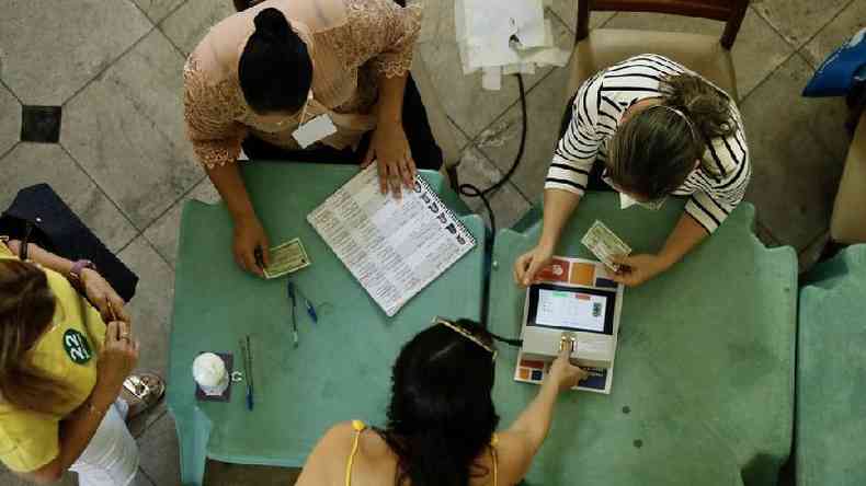 Eleitores e mesrios colhendo assinaturas e realizando biometrias