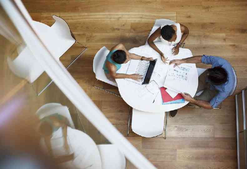 Trs pessoas trabalhando em uma mesa