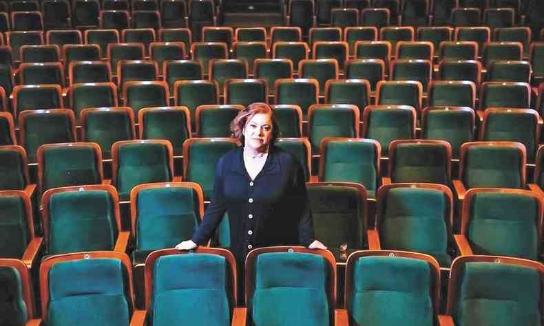 Sandra Campos, gestora do Cine Brasil, est em p em meio a cadeiras da plateia do teatro 