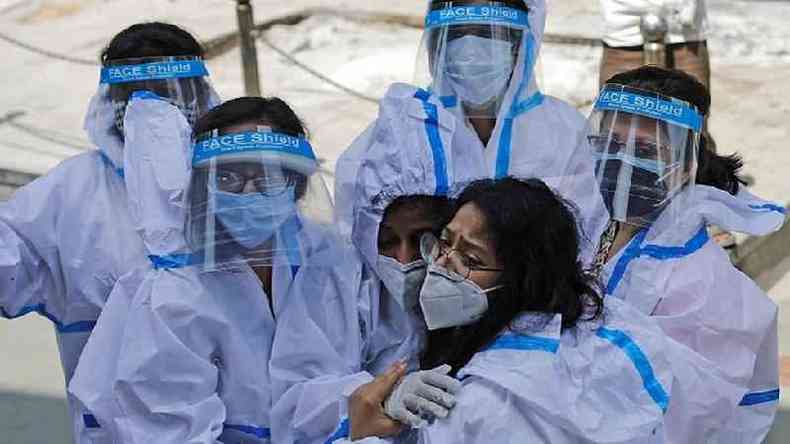 Grupo de trabalhadoras da sade com equipamento de proteo individual se abraa(foto: Reuters)