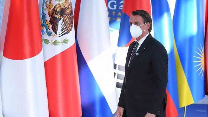 Bolsonaro caminha de mscara diante de bandeiras de outros pases