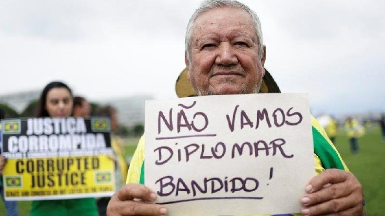 Senhor segurando cartaz que diz: No vamos diplomar bandido