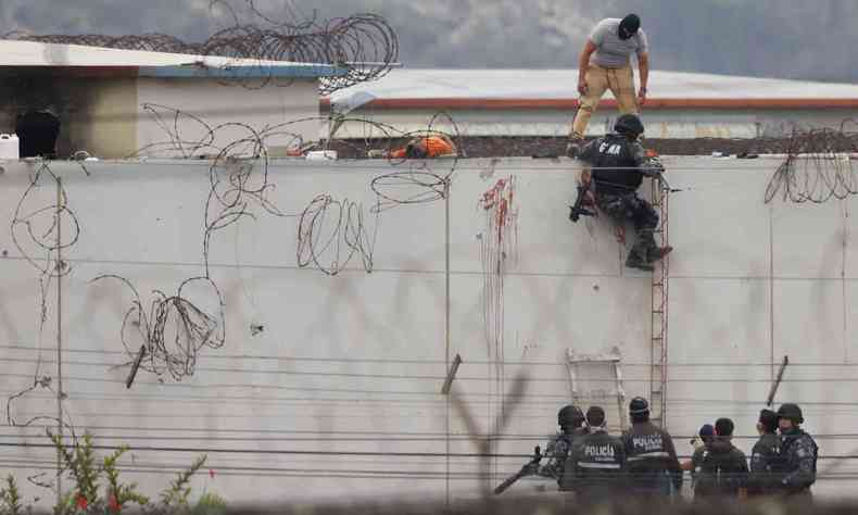 policial escala muro alto e com cercas de presdio no Equador onde 68 presos morreram em 12/11